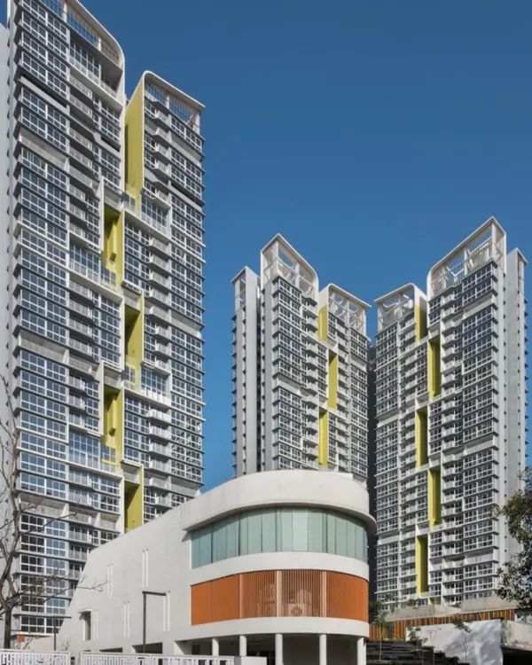 This view of our Serein project showcases how we design modern, high-density housing that feels both grand and livable. The architectural form is articulated with clean lines and strategic color accents, creating a dynamic facade against the clear sky.