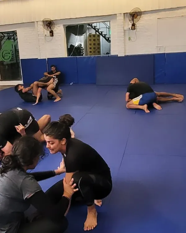 A wide shot of a busy no-gi class. Members are paired up, drilling techniques and getting in live rolls.