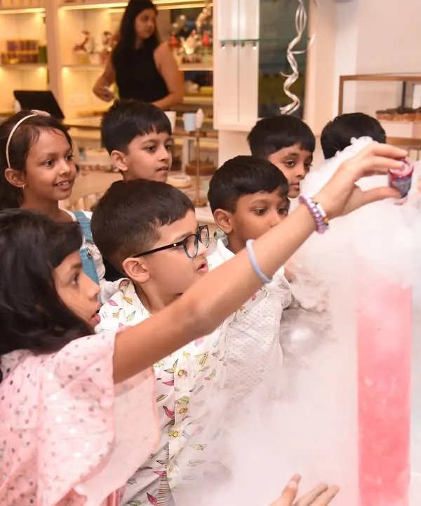 Children gather around, captivated by a hands-on science show with colorful, smoking beakers. This safe and exciting science activity is a huge hit at birthday parties, making learning fun.
