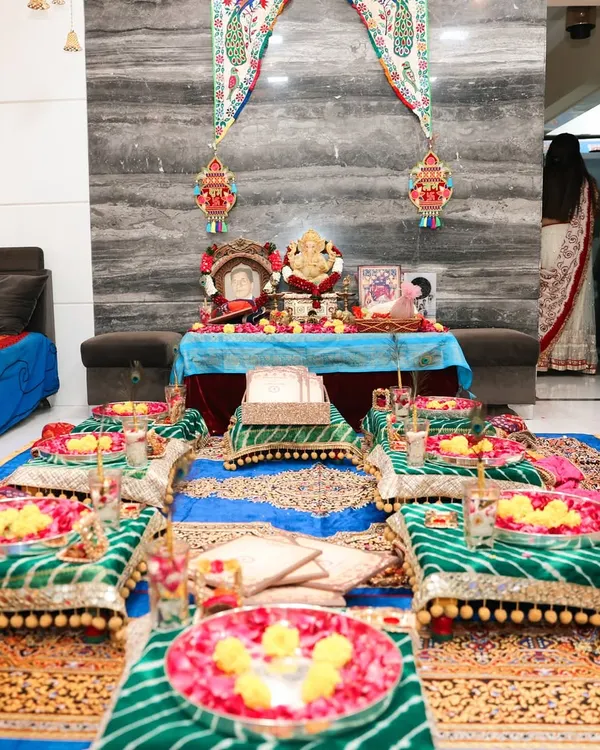 A closer view of the Lagan Lakhwanu setup, focusing on the ritual area. You can see the decorated bajots for seating, each with a plate of flowers, and the main table for the puja, all set against a traditional backdrop.