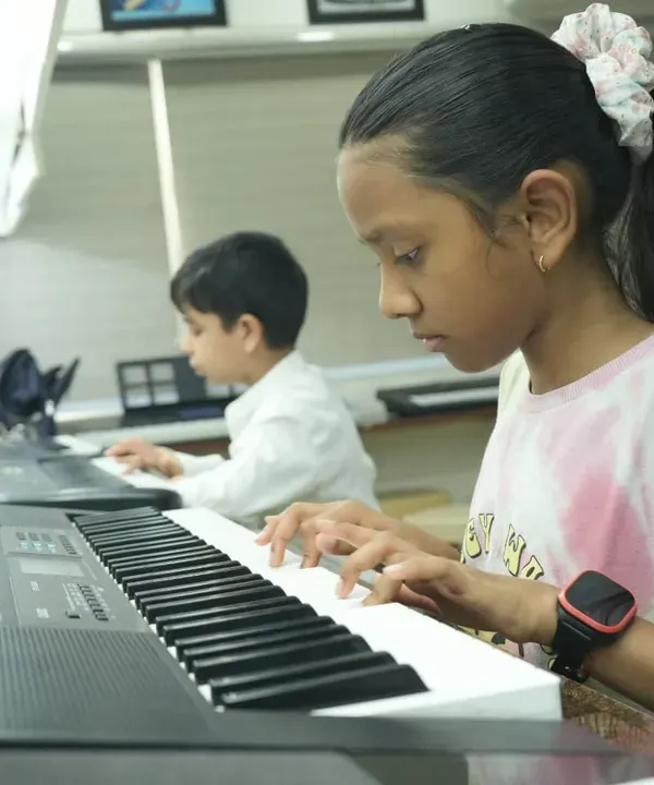 A young student practices finger placements on the keyboard, reading sheet music. Our classes focus on building strong fundamentals in both practical skills and music theory.