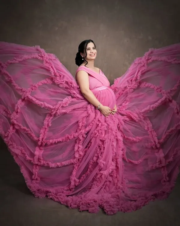 The butterfly effect. This dramatic pose with a flowing pink gown creates a stunning butterfly shape, symbolizing transformation and new beginnings. We love getting creative to produce unique, artistic maternity portraits.
