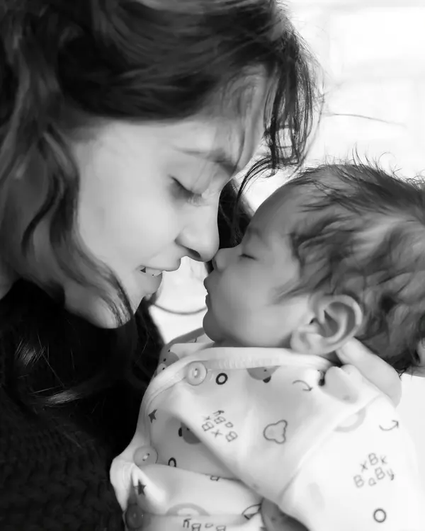 A tender black and white moment between a mother and her newborn baby. This style emphasizes the emotional connection.