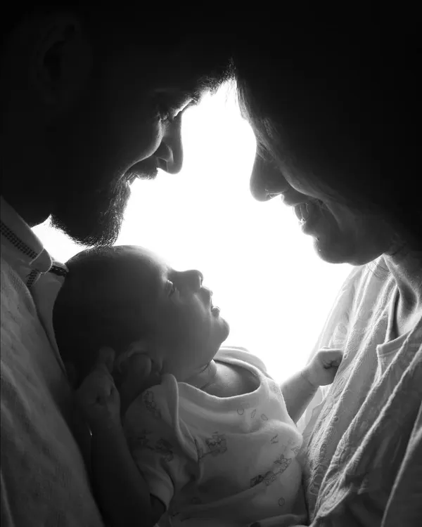 This dramatic, high-contrast silhouette captures the intimate bond between new parents and their baby. It's a powerful and artistic black and white portrait that focuses solely on their connection.