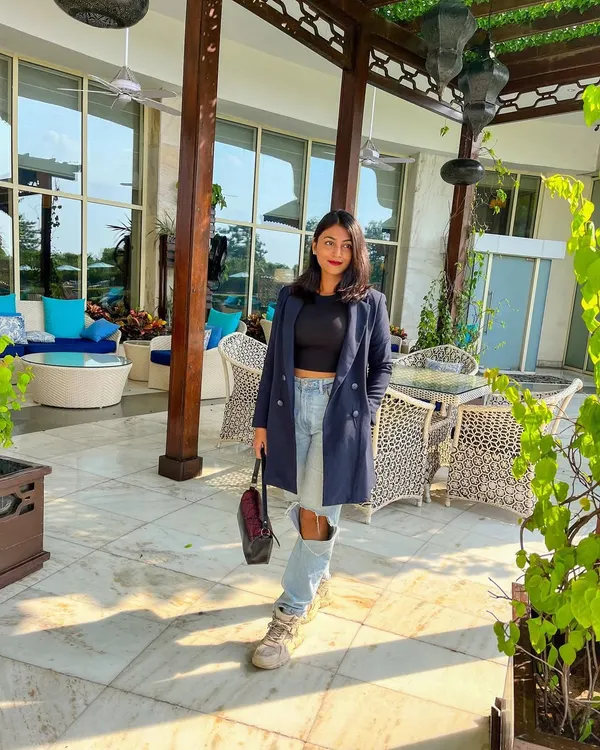 A great blazer is a cornerstone of power dressing. Here, I've styled a longline navy blue blazer with a simple black crop top and ripped jeans for a look that's sharp yet edgy.