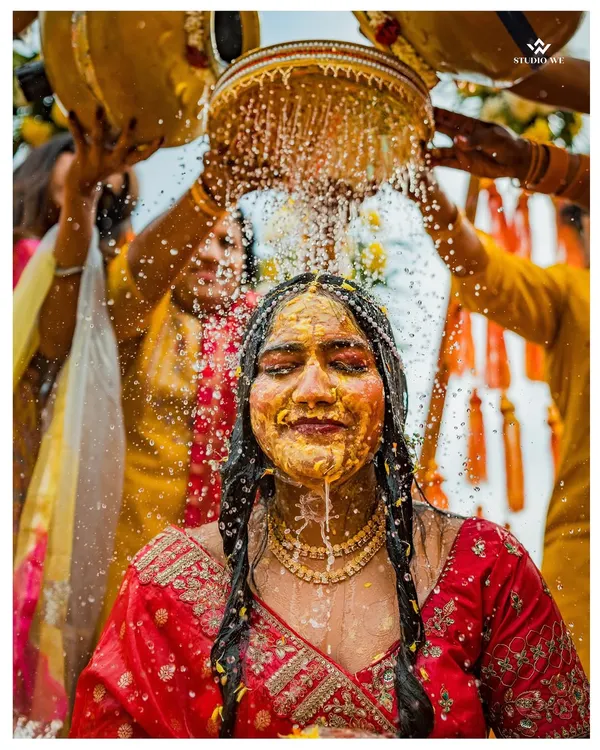 A bride is showered with water and turmeric during her Haldi ceremony, a moment of pure, unadulterated joy and tradition.