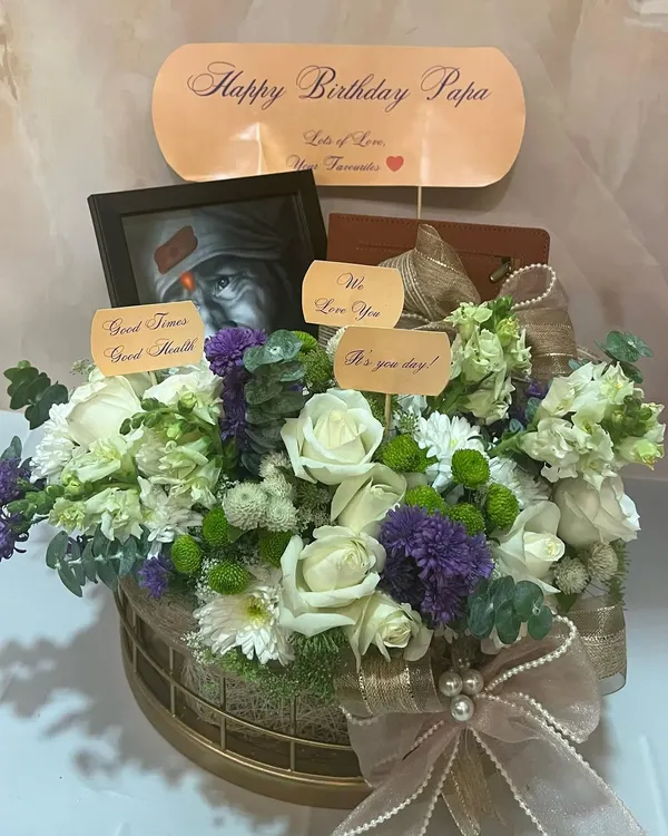 The perfect last-minute birthday delivery for a beloved father. This floral hamper includes a spiritual touch with a Sai Baba frame, a personalized note, and fresh white and purple flowers.