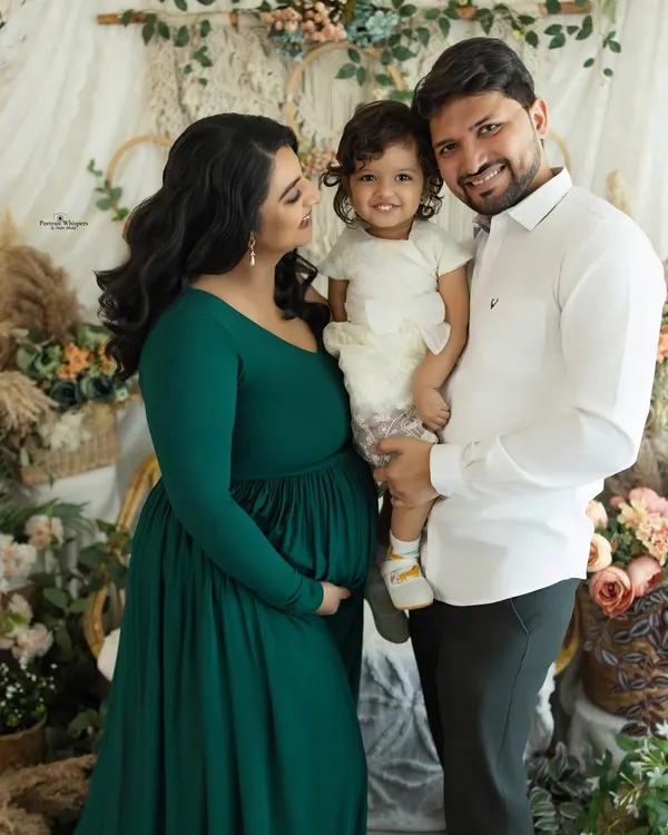 A happy family portrait in our cozy, boho-inspired studio setup. This image captures the joy of a growing family, with everyone smiling and embracing in a relaxed, natural way.