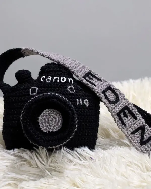 A unique, custom-made crochet camera pouch. This one was personalized with the brand 'Canon' and the name 'Eden' on the strap.
