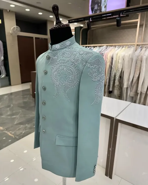A stunning pastel mint green Jodhpuri suit displayed on a mannequin. The delicate, tonal threadwork and bead embroidery on the shoulder and collar make this a sophisticated choice for a day event.