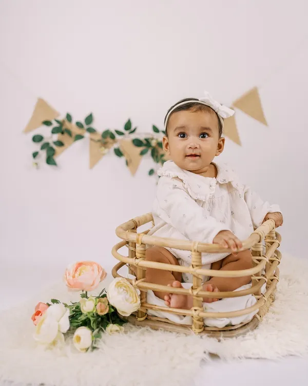 A perfect six-month "sitter session" portrait. This little girl, sitting up on her own in a sweet basket, is celebrating being halfway to one.