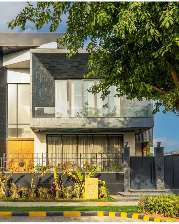 An angled view of our award-winning zinc-clad residence, highlighting the interplay between the textured shingle facade and the smooth, monolithic volumes. The large window openings are strategically placed to capture natural light while maintaining privacy for the residents.