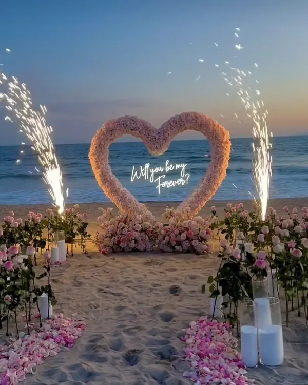 This is what a promise of forever looks like. I designed this dreamy beachside proposal with a custom floral heart arch, a neon sign, and perfectly timed pyrotechnics to create a truly unforgettable moment against the sunset.