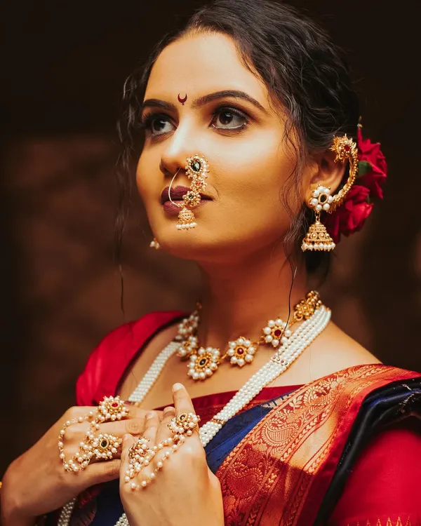 A classic Maharashtrian bridal look. The warm, dramatic lighting highlights the intricate details of the jewellery, the nath, and the beautiful expression.