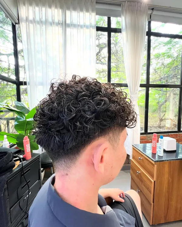 This men's perm adds incredible texture and volume. Paired with a low taper fade, it's a modern and stylish look.