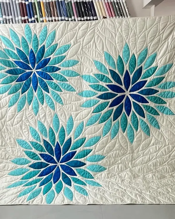 This is our magnificent Sea Glass Quilt, a true labor of love. Each piece of fabric is carefully chosen and appliquéd to create a stunning visual effect, reminiscent of sunlight on water. The intricate longarm quilting adds texture and depth, making it a perfect statement piece of wall art.