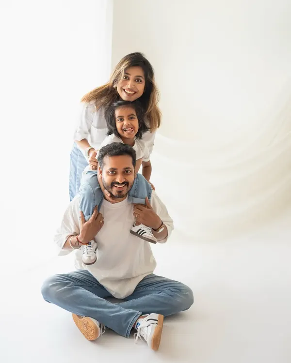 The classic family totem pole! A daughter on her dad's shoulders with mom peeking from behind. This is such a fun and happy pose for a studio family portrait.