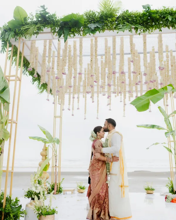 A tender moment under a beautiful floral mandap on a Goan beach. The groom kisses the bride's forehead as the ocean stretches out behind them. This is the quiet intimacy I strive to capture amidst the celebration.