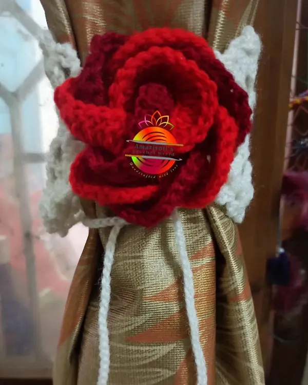 An elegant curtain tie-back featuring a large, intricately crocheted red rose on a white band. This design adds a touch of classic romance to any window dressing.