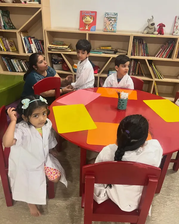 Our Science Camp is in full swing. Here, a group of young scientists in their lab coats are gathered around the table, ready for their next lesson.