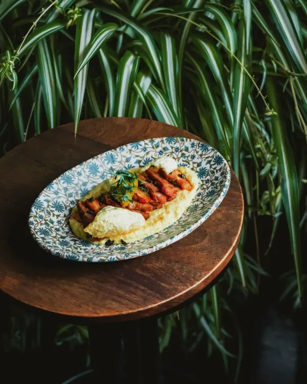 This smoked pork belly, served on a beautiful patterned plate, perfectly encapsulates the combined brilliance of our chefs: the warmth of comfort and the depth of story.