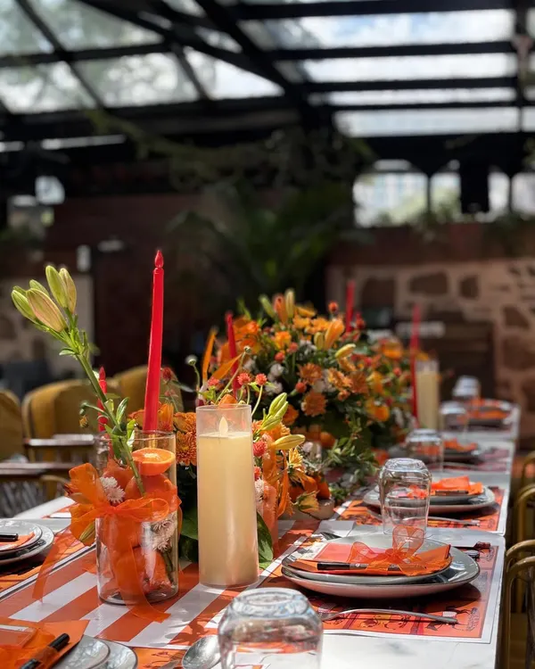 An elegant table setting for the Hermès-themed baby shower, with a long floral runner, tapered candles, and custom place settings.