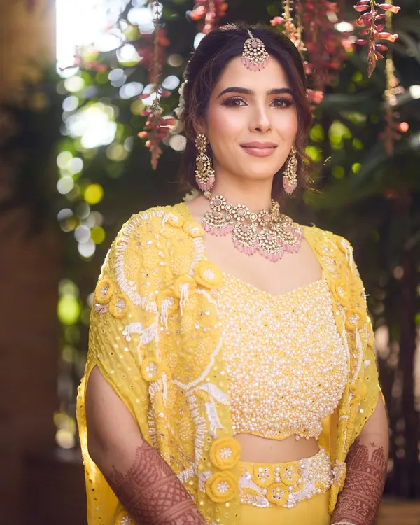 A perfect blend of tradition and glow for a Haldi ceremony. The bride's makeup features soft pink tones that beautifully complement her yellow outfit.