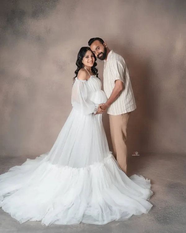 An ethereal and dreamy maternity portrait. The flowing white gown and soft lighting create a truly angelic look for the mom-to-be in this studio session.
