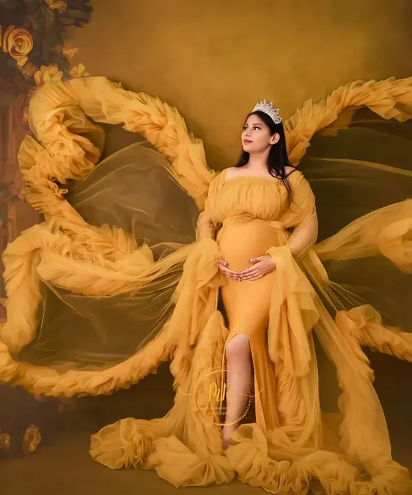 A regal portrait featuring our popular yellow butterfly gown. The fabric extends like wings against a floral backdrop, creating a powerful and artistic statement for a solo maternity shoot.