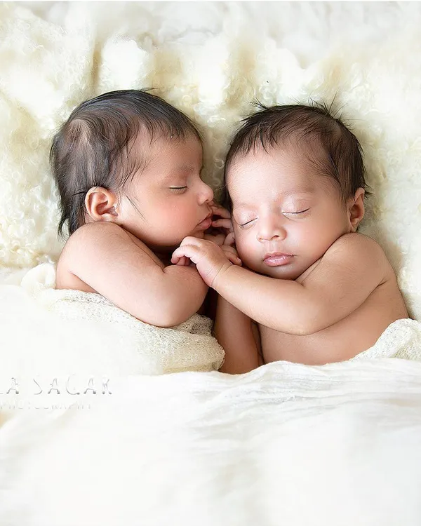 A quiet, tender moment between newborn twins. I use a simple, soft white blanket to create a cloud-like bed, ensuring the focus remains on their peaceful sleep and connection.