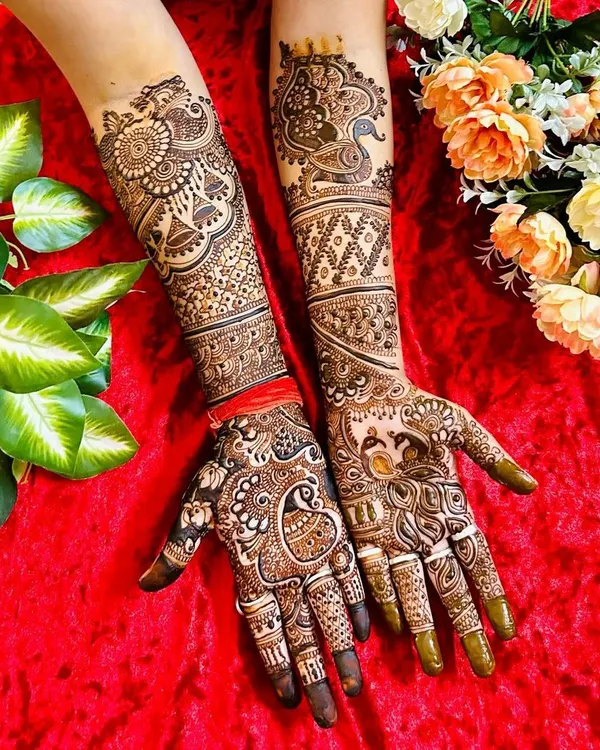 A complete view of a grand bridal mehndi design. This full-coverage look features peacocks, paisleys, and floral patterns, extending from the fingertips to the elbows for a stunning effect.