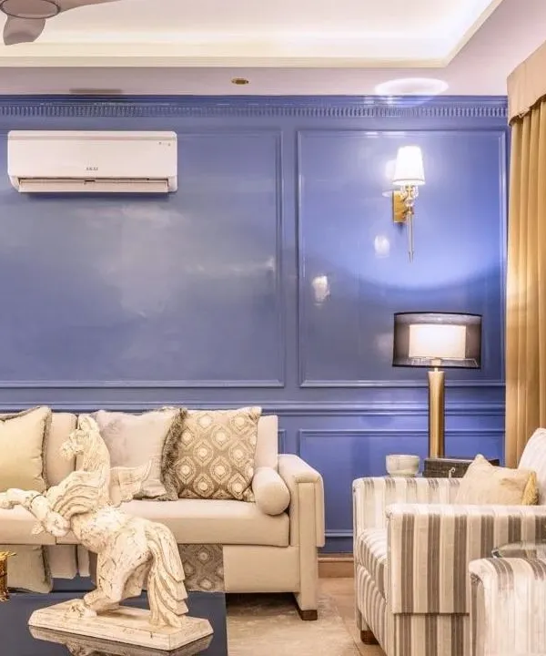 A complete living room setting we designed, featuring a neutral-toned sofa and striped accent chairs against a rich periwinkle blue wall with classic moulding. The space is anchored by a dark, contemporary coffee table, creating a balanced and inviting atmosphere.