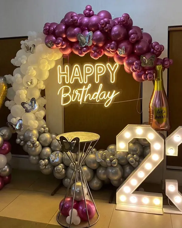 A glamorous 23rd birthday setup. This features a balloon ring with chrome and white balloons, a 'Happy Birthday' neon sign, and large marquee numbers.