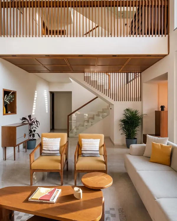 **Amber House, Ahmedabad:** The double-height living space is the core of this home, with a lowered wooden ceiling at the entrance to create a more intimate, welcoming scale. Vertical wooden slats on the upper level unify the space and create a beautiful interplay of light and shadow.