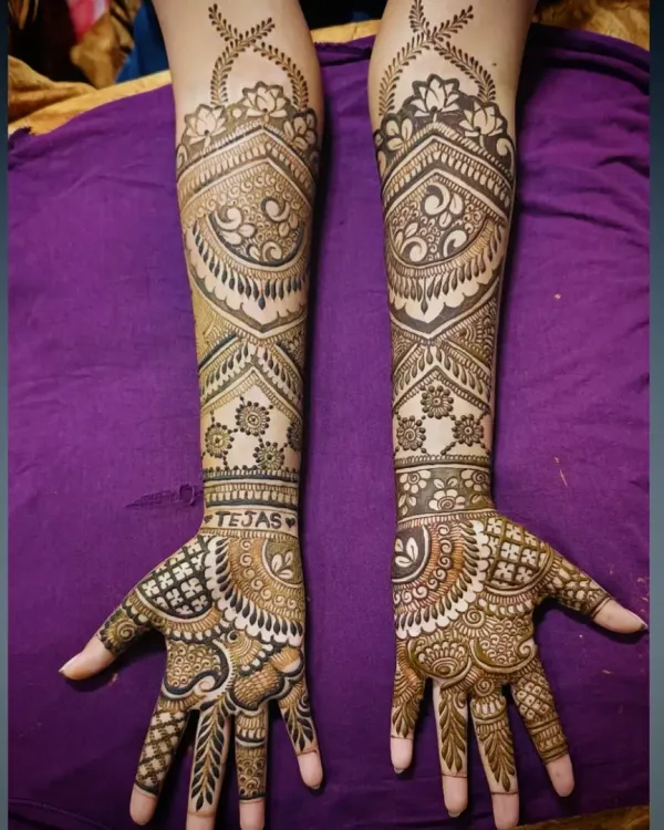 A close-up of the bridal mehandi for Tejas's bride, with his name beautifully integrated into the design on her wrist.