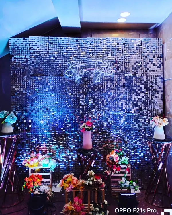 A glamorous photo booth featuring a silver shimmer wall that sparkles under blue lighting. A 'Better Together' neon sign adds a romantic and modern touch, making it a perfect spot for couple and guest photos.