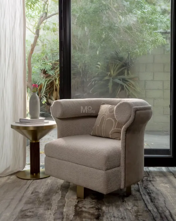 The Sienna Curve Armchair, with its distinctive curved backrest and 360-degree swivel base. Upholstered in a luxurious bouclé fabric with a smooth velvet accent, it's a statement piece perfect for a reading nook or bedroom lounge.