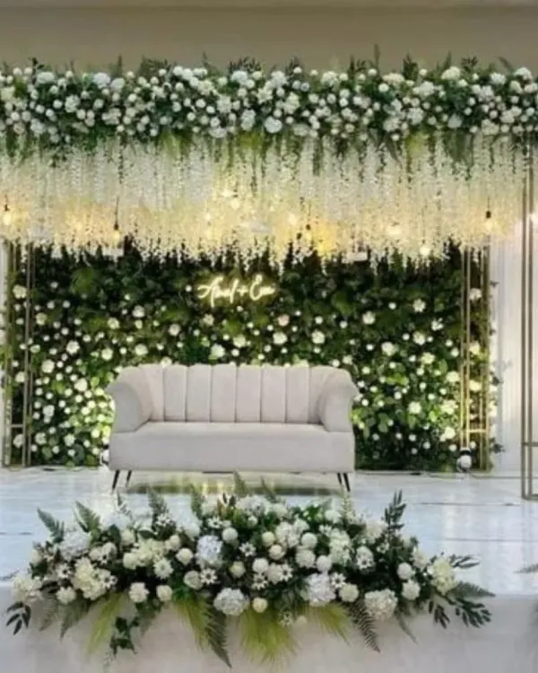 This is the kind of grand, beautiful stage I love to create for receptions and engagements. I use a full green wall, hanging white flowers, and a custom neon sign to make a stunning backdrop for your special day.