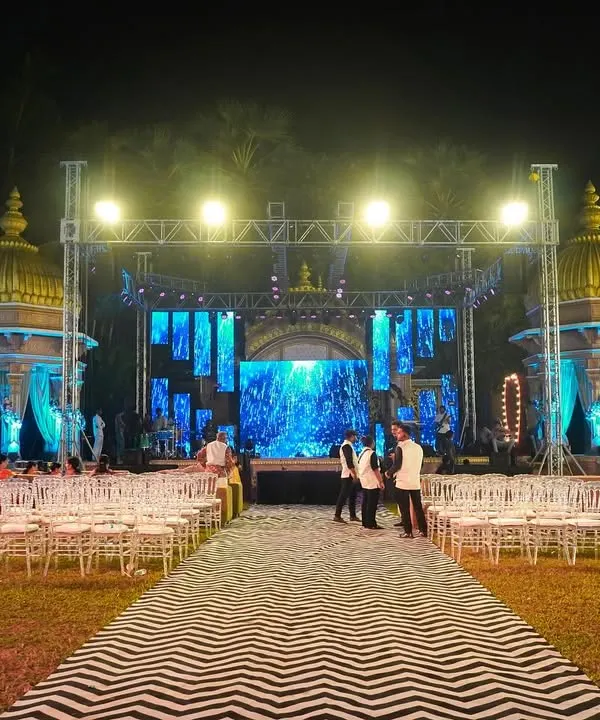 A grand outdoor stage setup for a Sangeet night, complete with a large LED screen backdrop and professional lighting rig. This creates a concert-like feel for the performances.