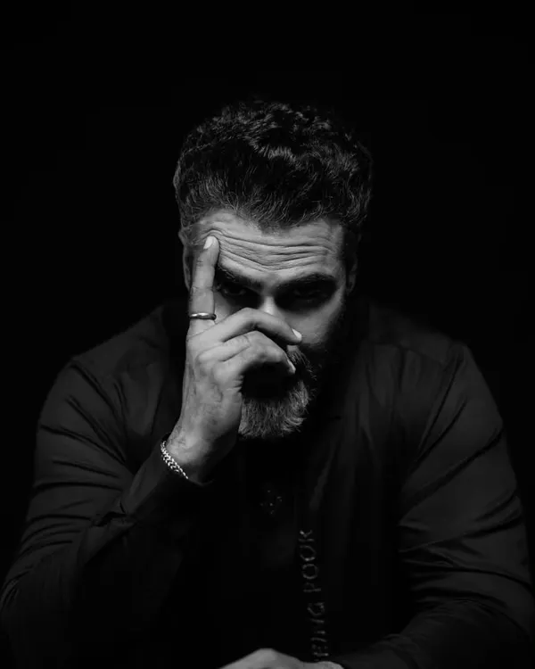 A study in stillness and thought. This low key portrait uses deep shadows to draw all attention to the subject's intense expression, creating a frame that feels like a scene from a film.