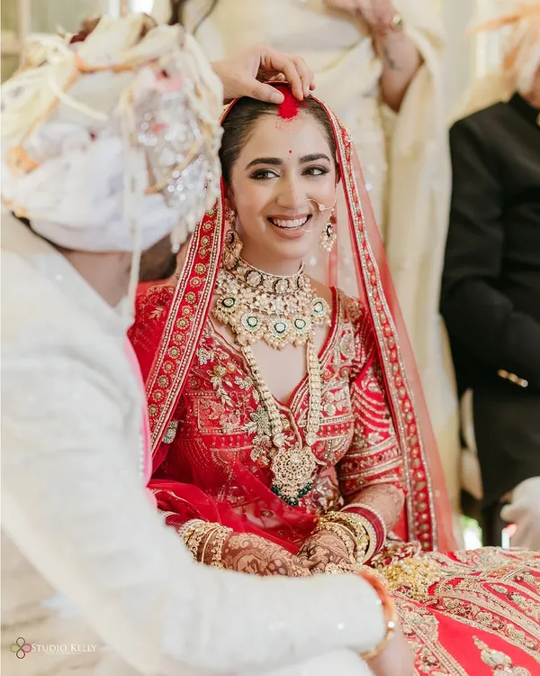 A beautiful, candid moment during the ceremony, capturing the bride's joyful smile as the groom applies the sindoor.