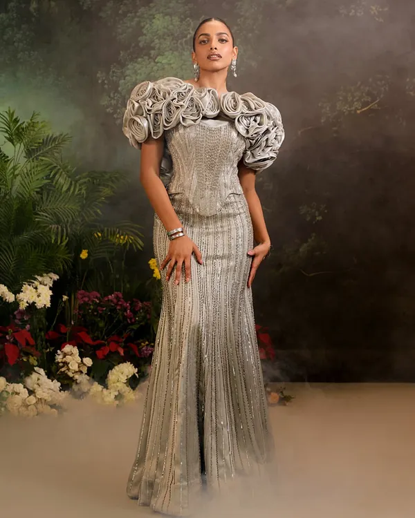 The Bellerose Gown in silver, featuring a fully embellished mermaid silhouette and dramatic 3D ruffled sleeves. This piece is a testament to sculptural, wearable art.