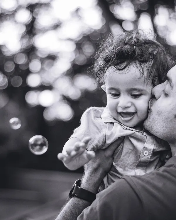 A father’s gentle kiss for his baby, surrounded by floating bubbles. We believe these simple, unposed moments are the ones that tell the most powerful stories, and we love capturing them in timeless black and white.