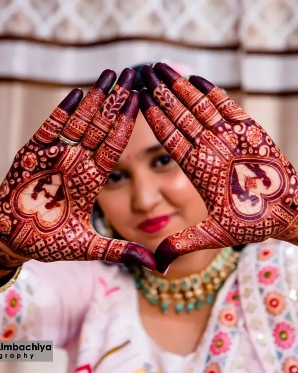 A beautiful shot of an engagement bride showcasing her mehendi. The design features personalized initials within hearts, a popular choice for engagement ceremonies.