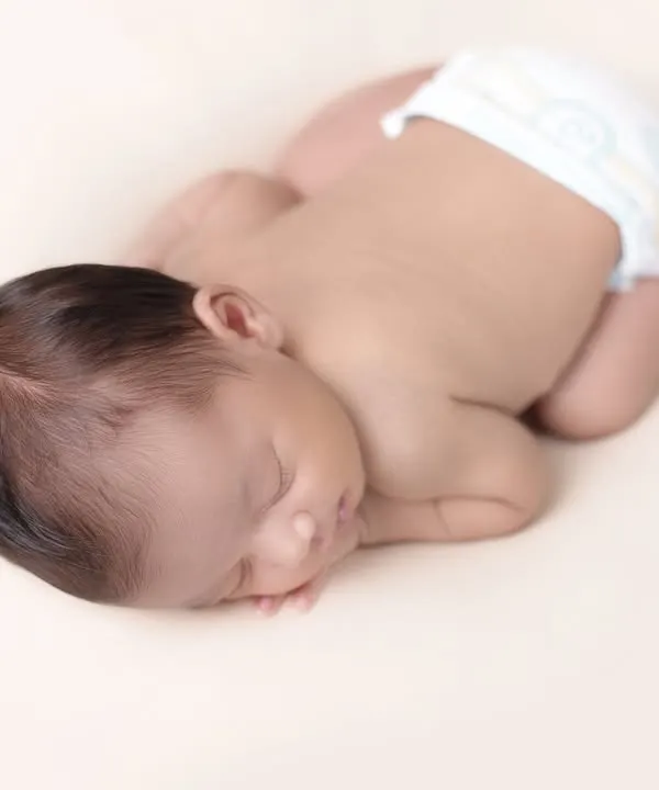 The simple, pure beauty of a newborn. This minimalist pose focuses on the tiny, perfect details of your baby, from their curled fingers to their peaceful expression, creating a timeless and classic newborn portrait.