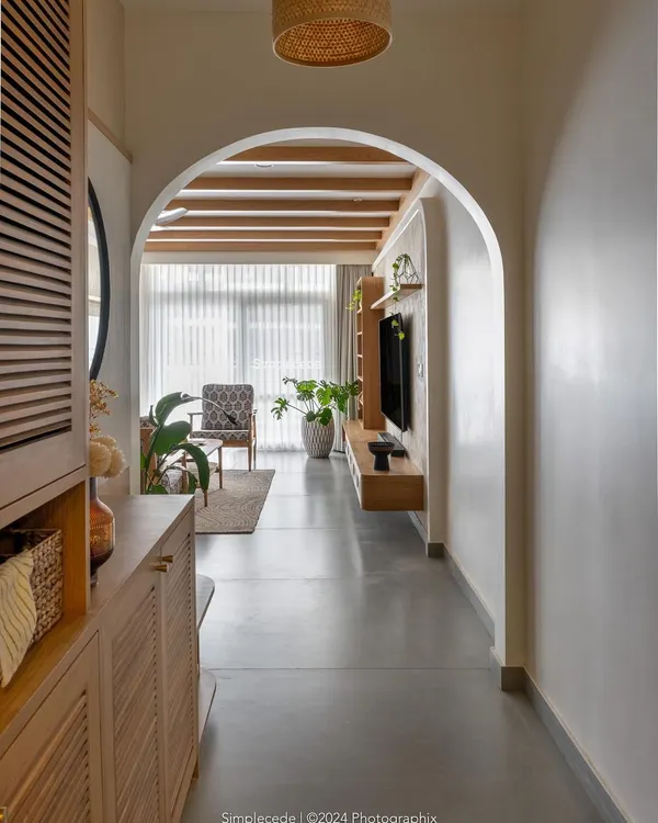 We believe a home's entrance should be an invitation to comfort. In our 'Cover me in Sunshine' project, we created this arched entryway that frames the living area, drawing the eye towards the warm, light-filled space. The exposed ceiling rafters and custom louvered cabinetry introduce the earthy, modern cottage style that defines this home.