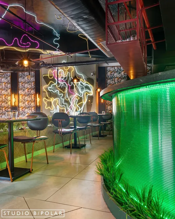 An overview of Burosu restaurant, where a glowing green fluted glass bar and custom neon art create a vibrant, street-style pulse. The design uses layers of light, texture, and color to create an immersive pan-Asian dining experience.
