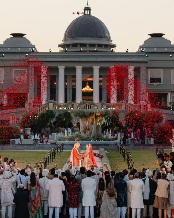 A shower of red rose petals rains down as the couple exchanges garlands, framed by the magnificent Raffles Udaipur. I orchestrate these peak moments with pyrotechnics and confetti for a truly spectacular visual.