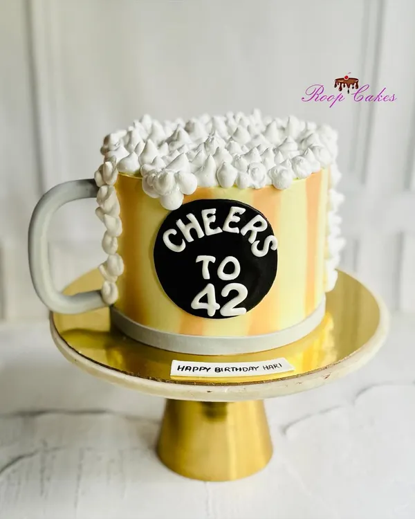Cheers to 42. This fun birthday cake is shaped like a frothy mug of beer, complete with a handle and overflowing whipped cream foam. It's a perfect and playful cake for a beer lover's celebration.