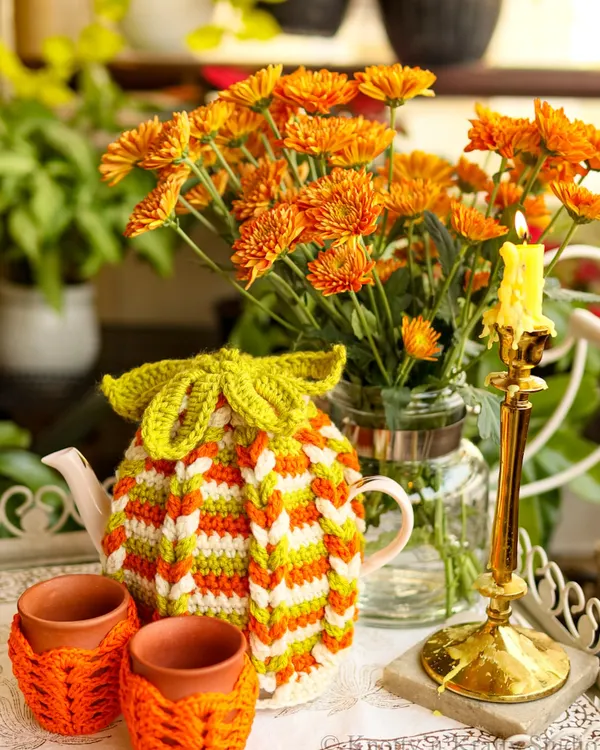 A cozy autumn tea setting featuring my striped tea cozy with a leaf-tie detail, paired with matching orange kulhad covers. This set is perfect for keeping your chai warm on chilly days.